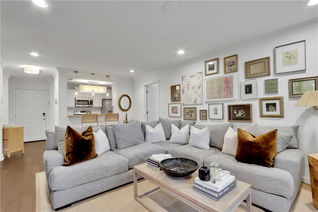 a living room with furniture a rug kitchen view and a window