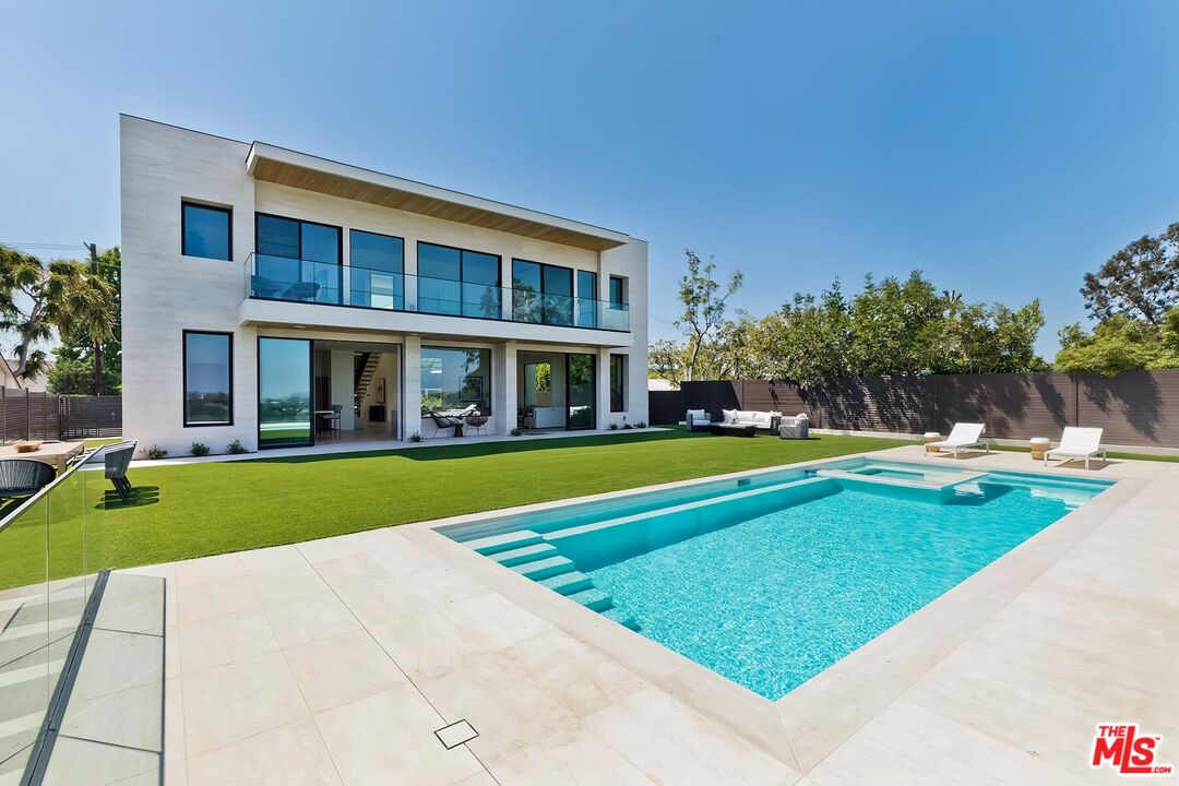 a view of swimming pool with lawn chairs and plants