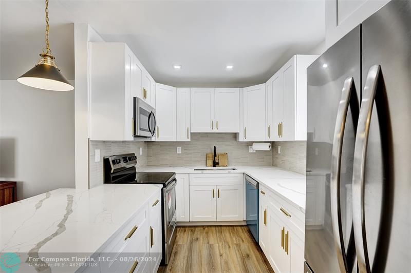 a kitchen with stainless steel appliances granite countertop a refrigerator sink and white cabinets