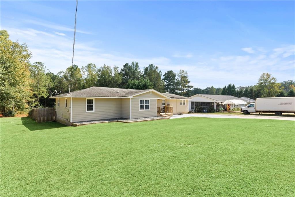 a house that is sitting in the grass with large trees and plants