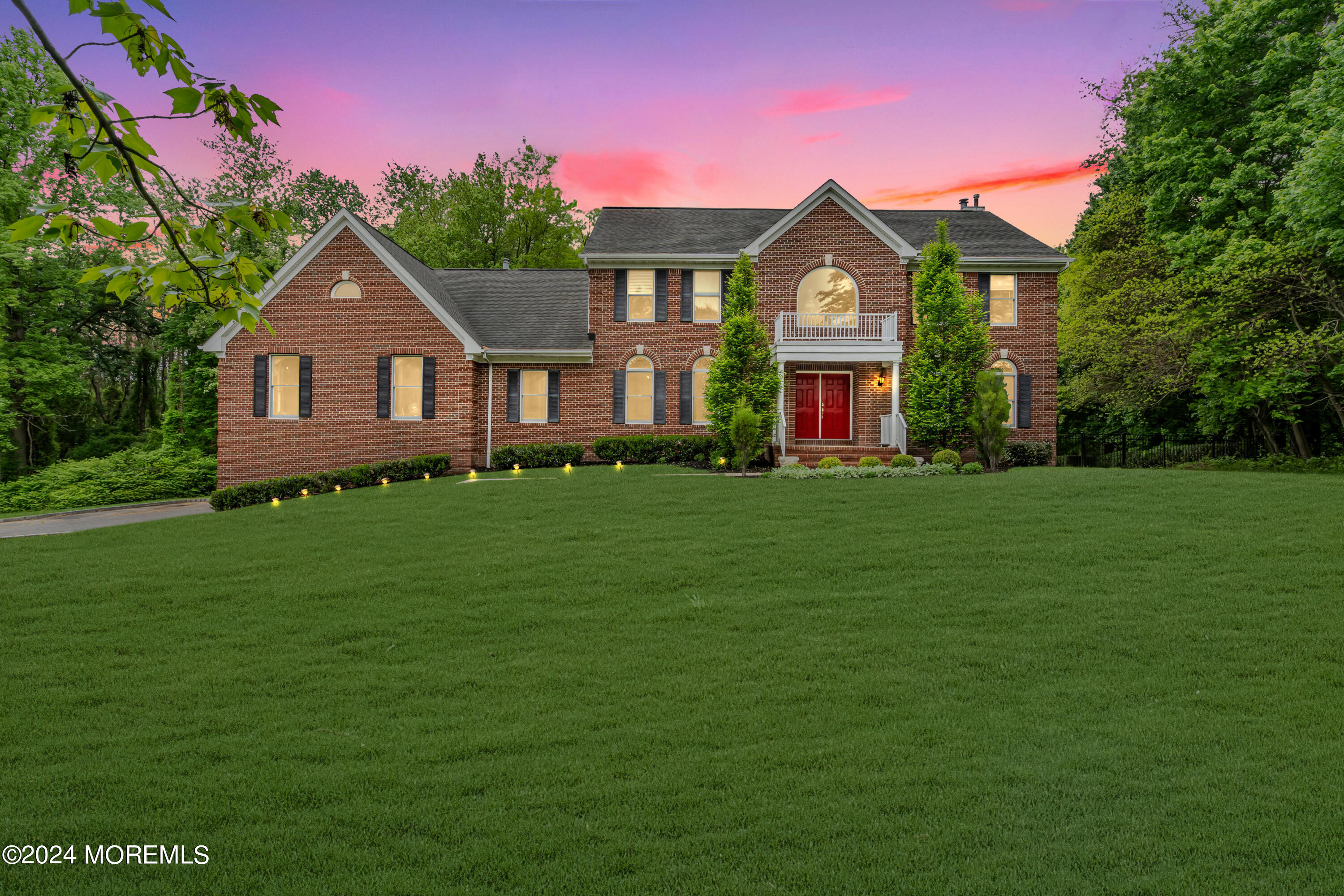 a front view of a house with garden and trees