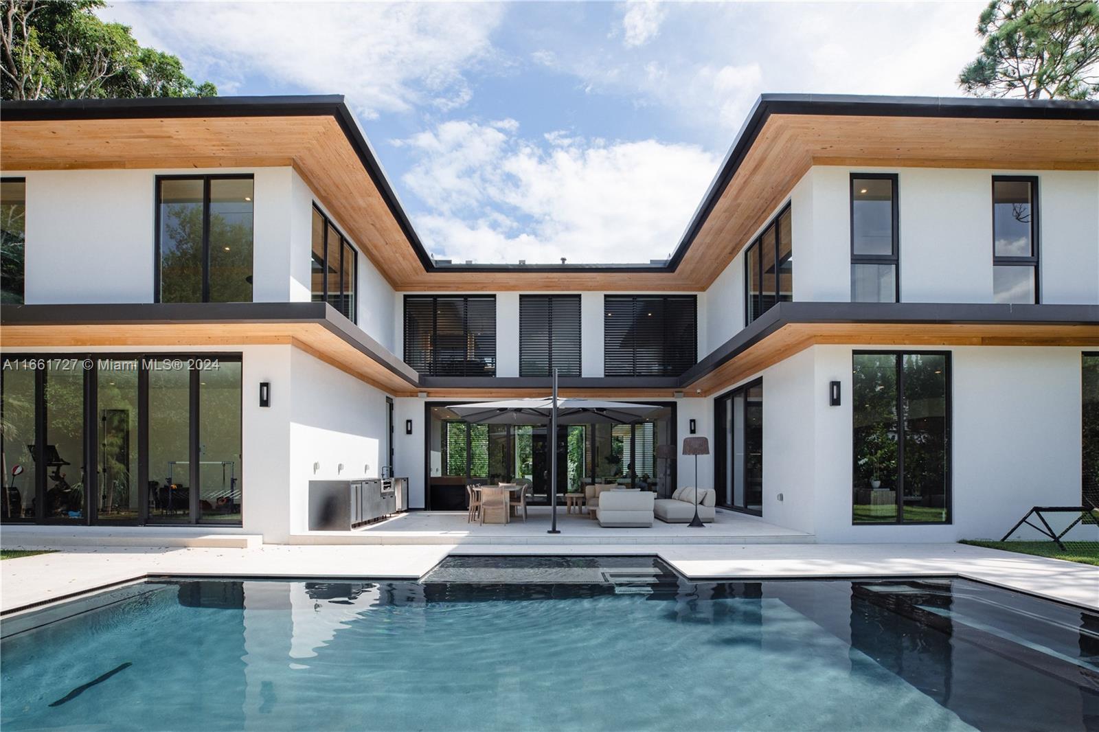 a view of a white building with a large pool and couches chairs