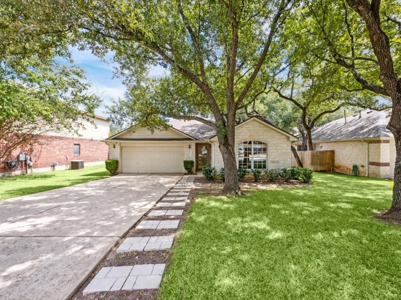 a front view of a house with a garden and trees