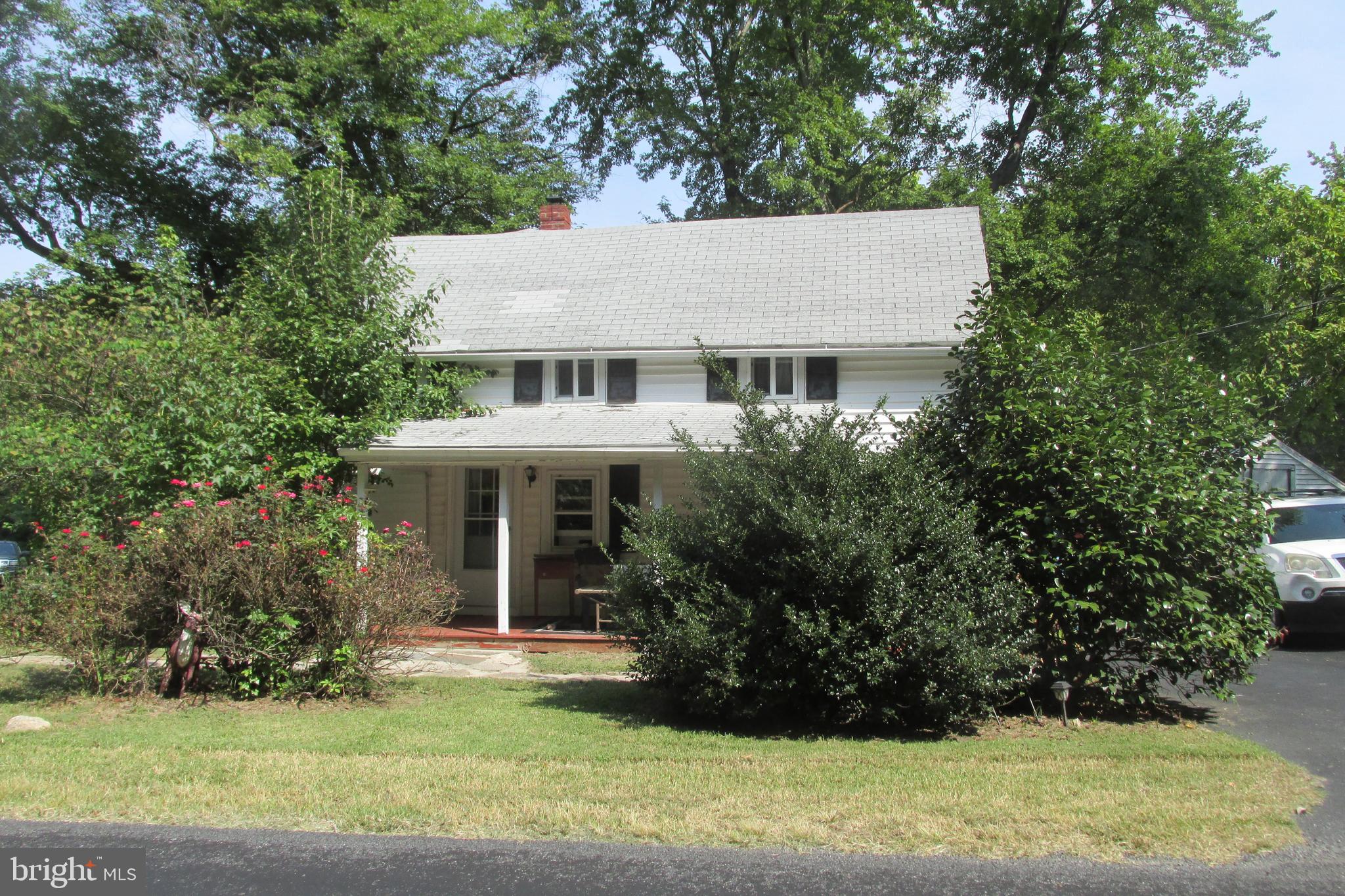 a view of a white house next to a yard with big trees