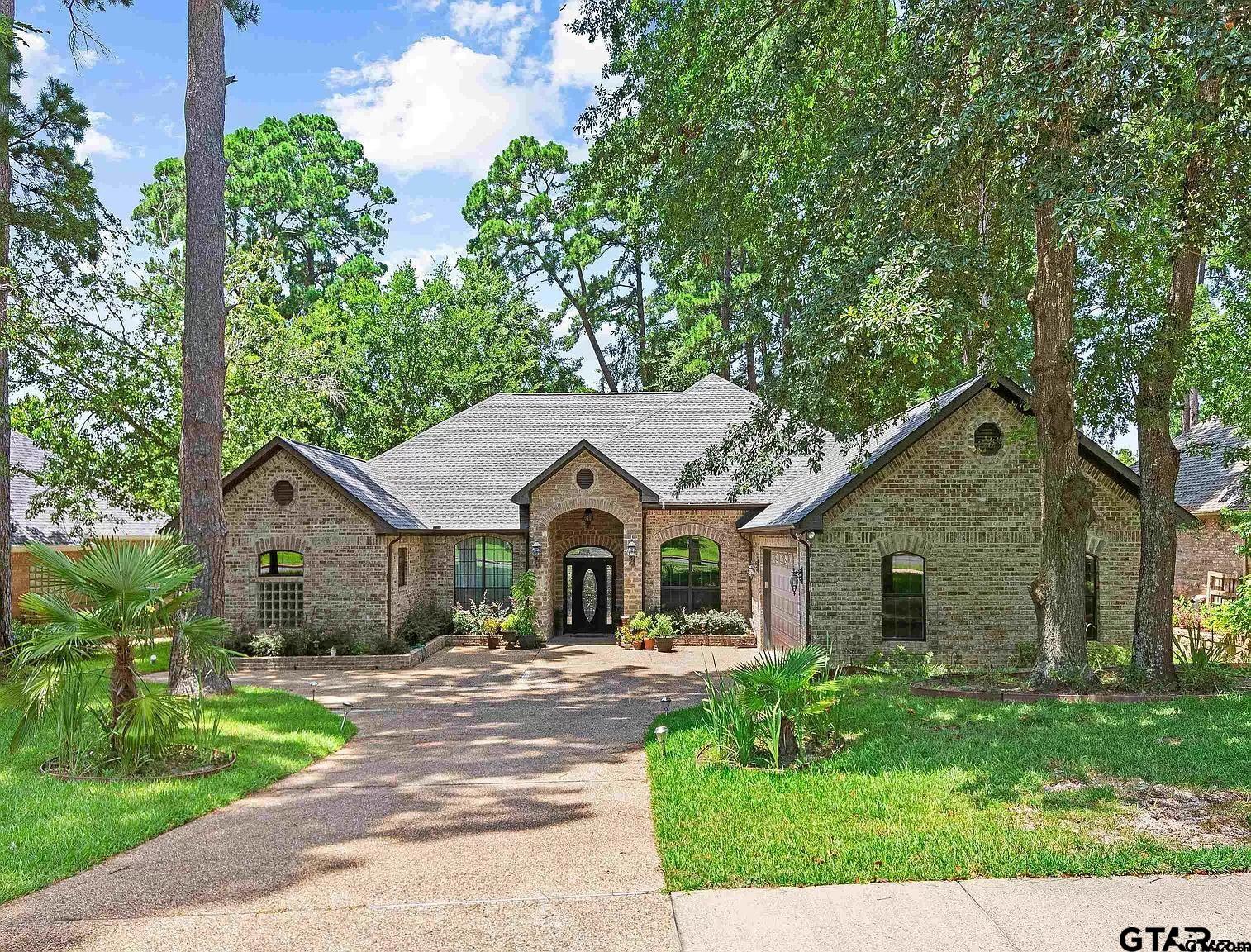 a front view of a house with a garden and trees