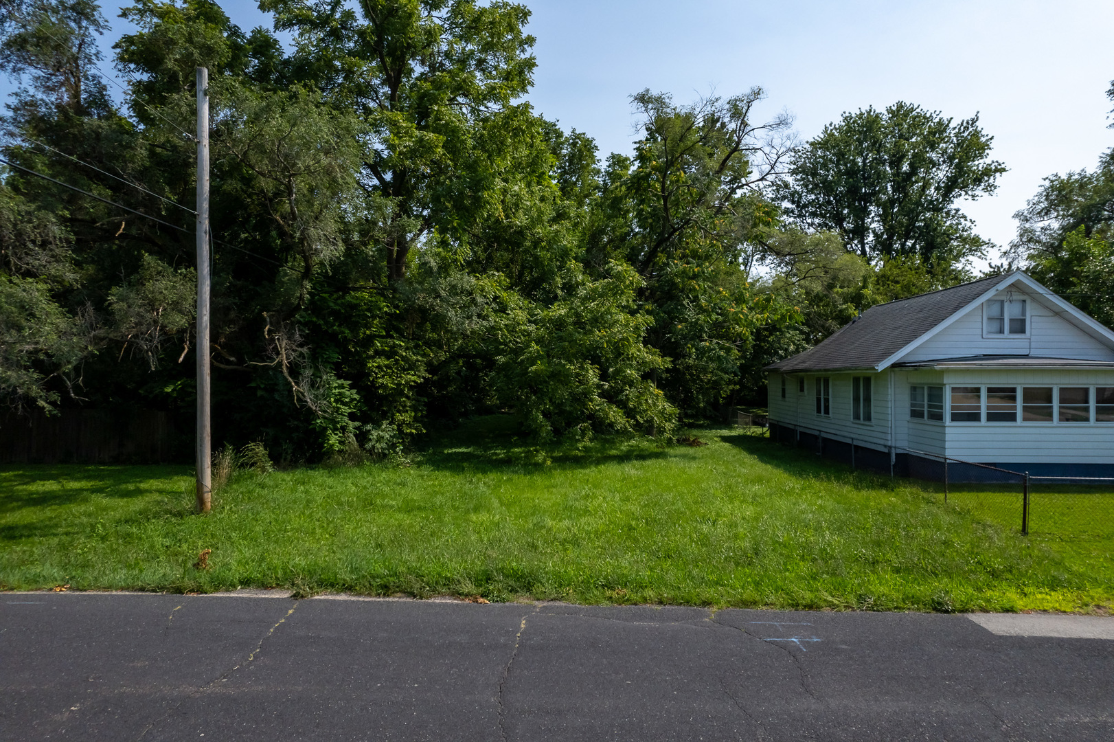 a view of a house with a big yard plants and large trees