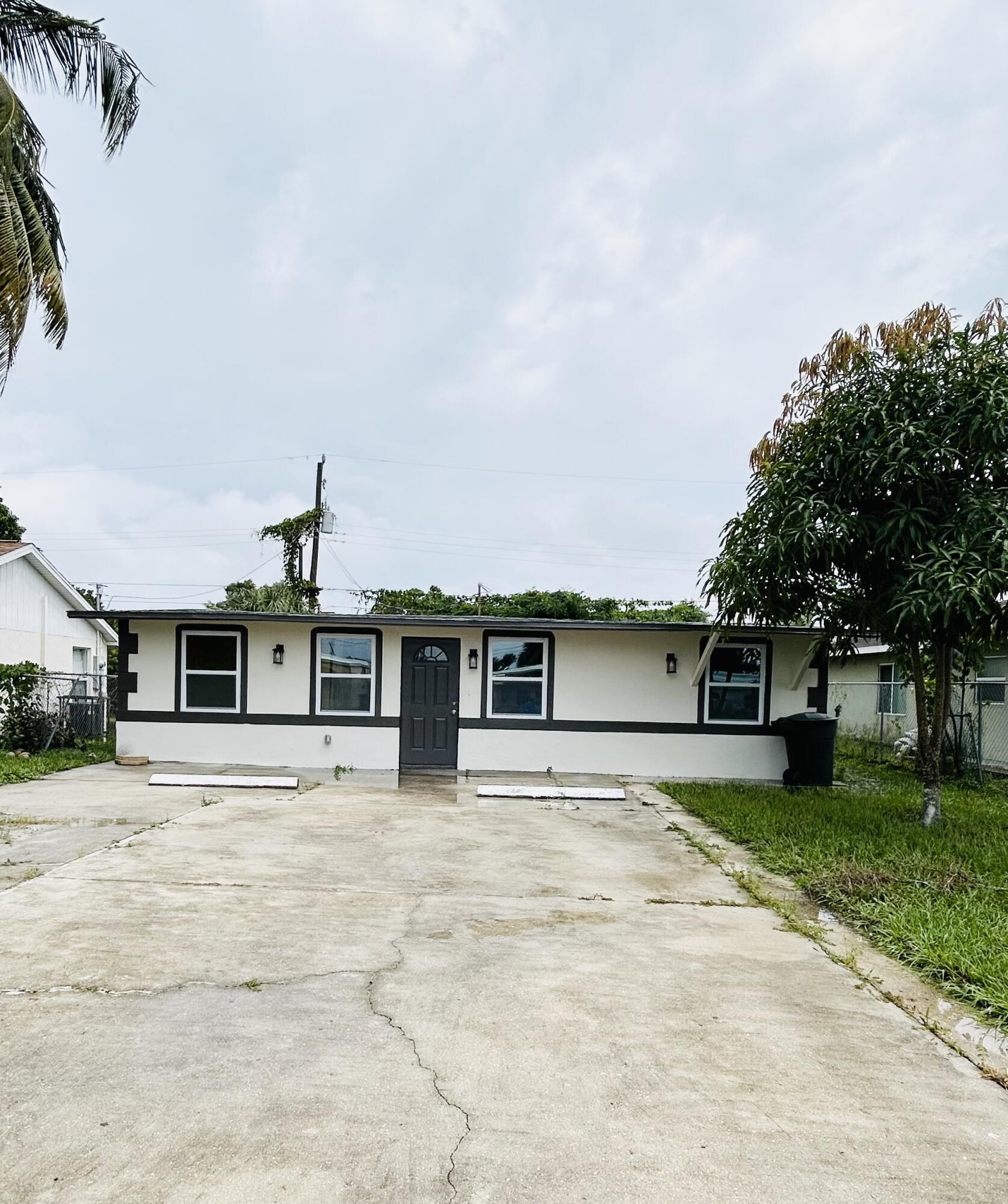 a front view of a house with a garden and trees