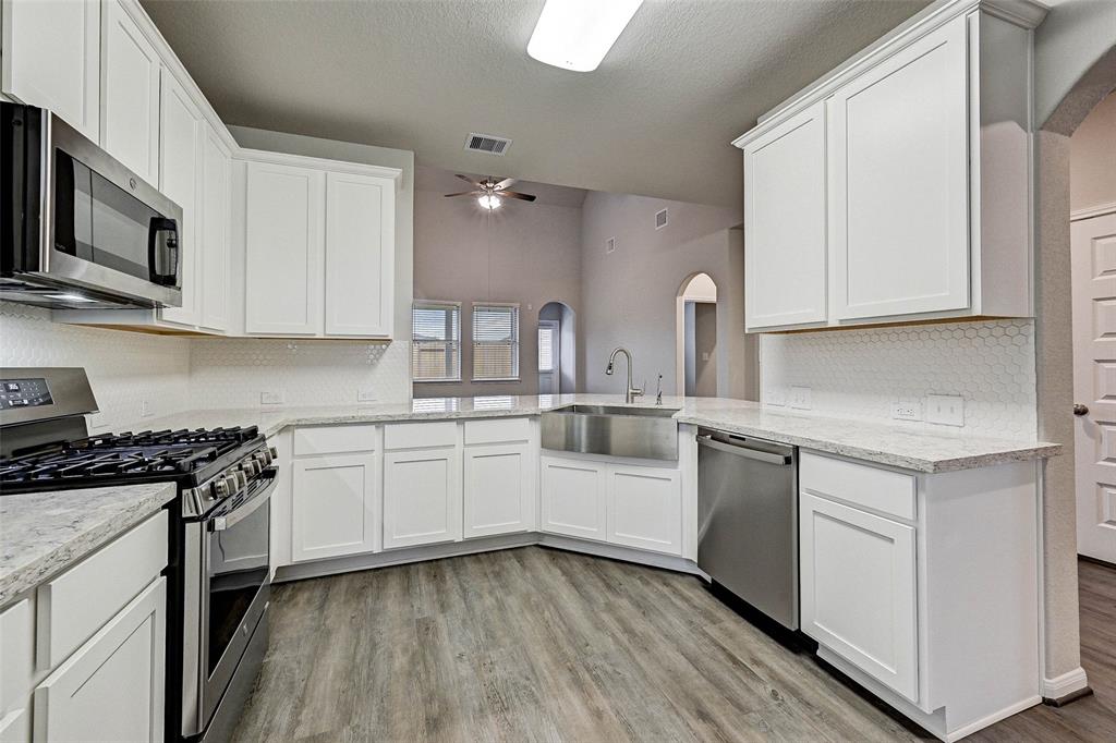 a kitchen with stainless steel appliances granite countertop a stove a sink and white cabinets