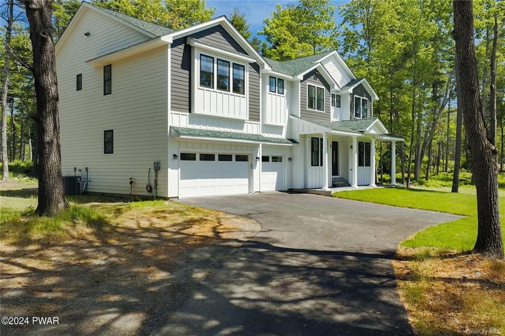 View of front of home featuring a garage, central air condition unit, and a front lawn