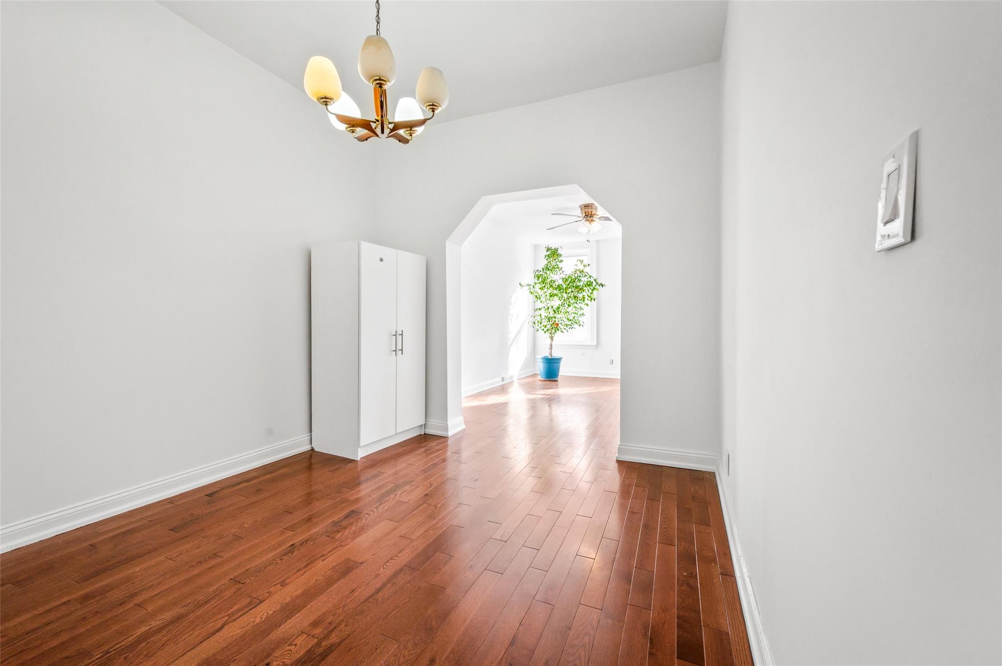 Empty room featuring dark wood-type flooring and ceiling fan with notable chandelier