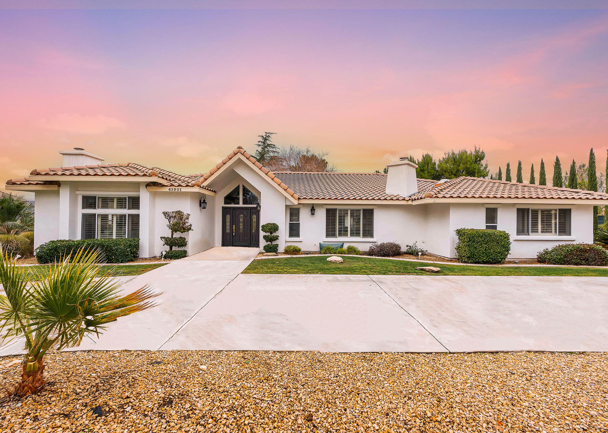 a front view of a house with a yard and potted plants