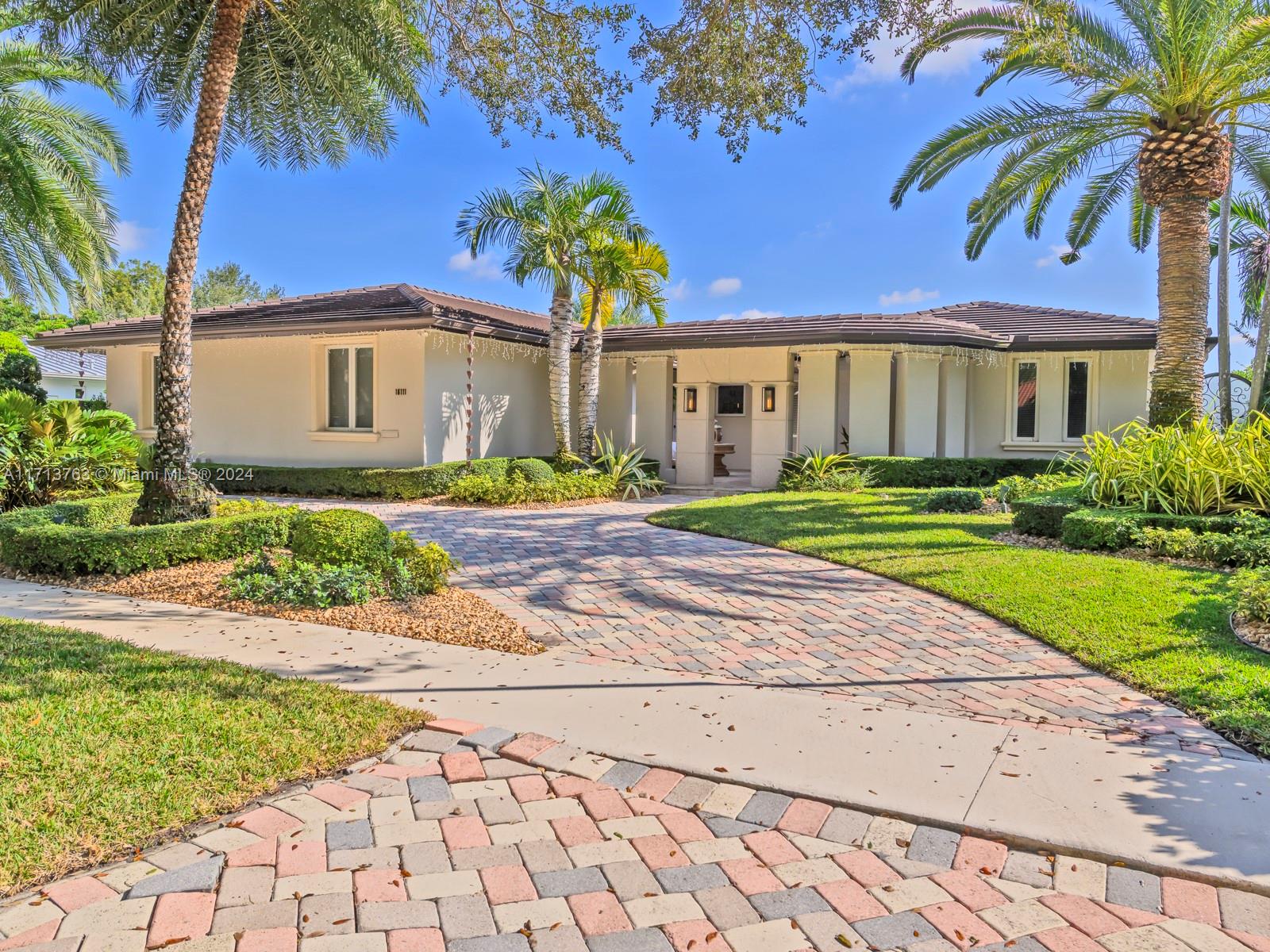 a front view of a house with a yard and potted plants