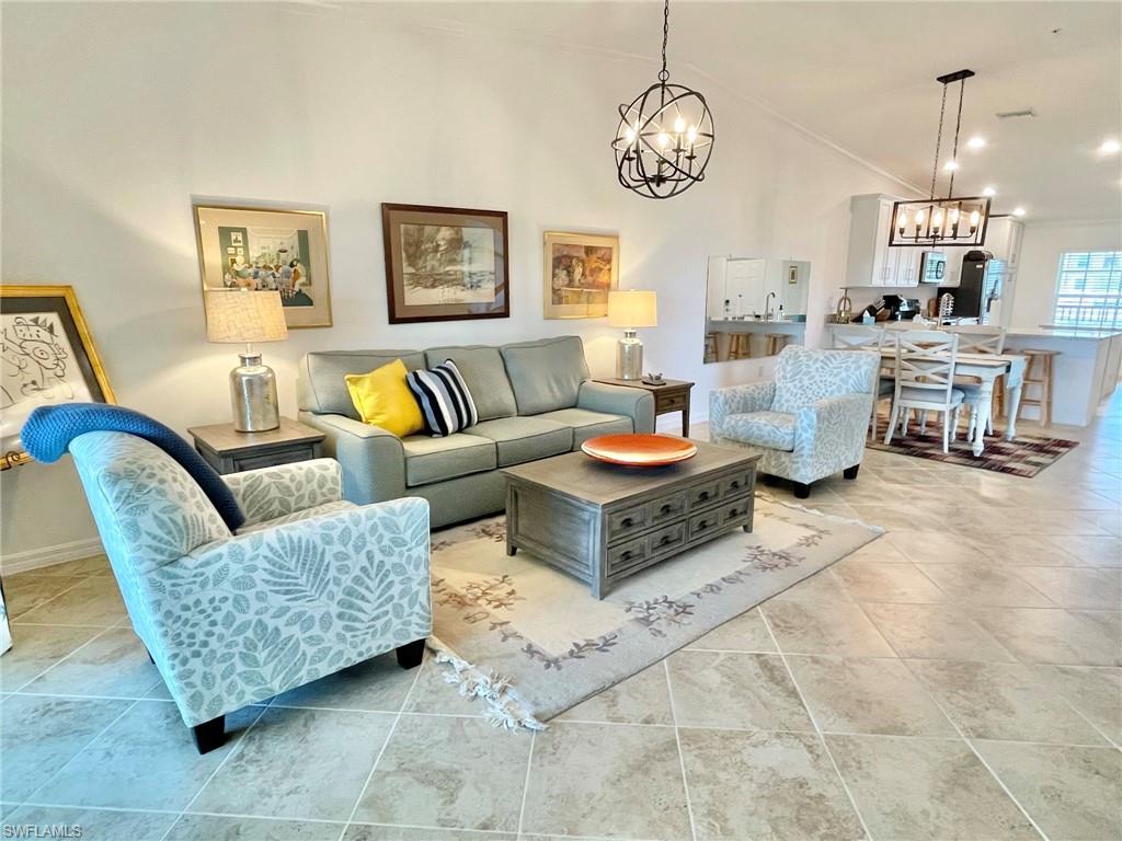 a living room with furniture kitchen view and a chandelier