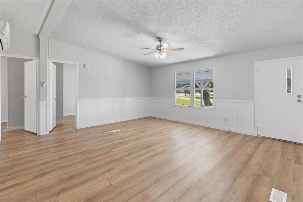 an empty room with wooden floor ceiling fan and windows