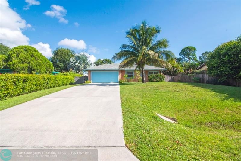 a front view of a house with a yard and palm trees