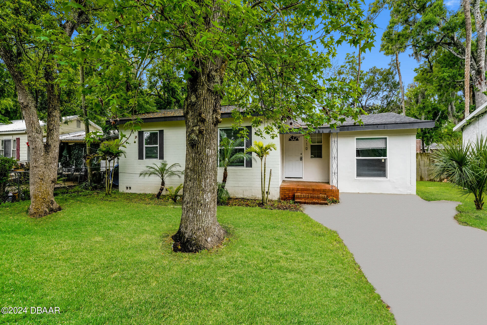 a front view of house with a garden and trees