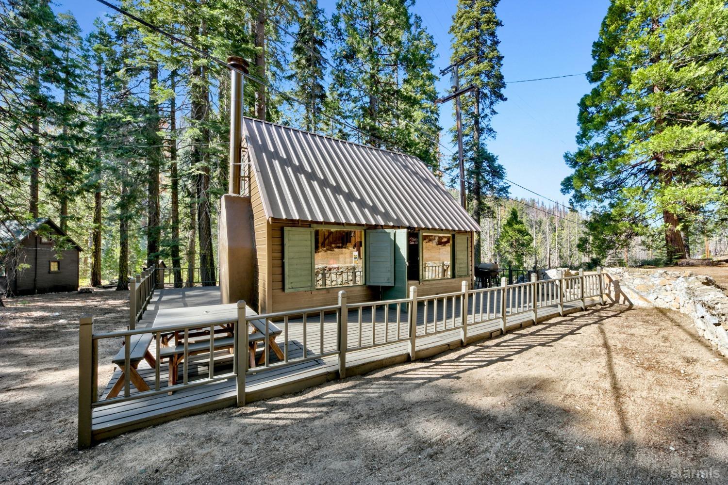 a view of a house with large tree and wooden fence