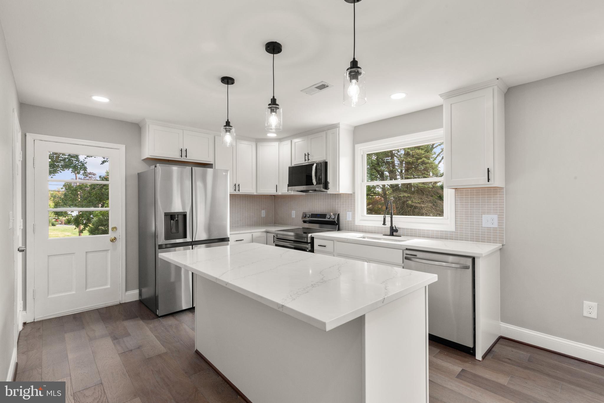 a kitchen that has a sink a center island stainless steel appliances and cabinets