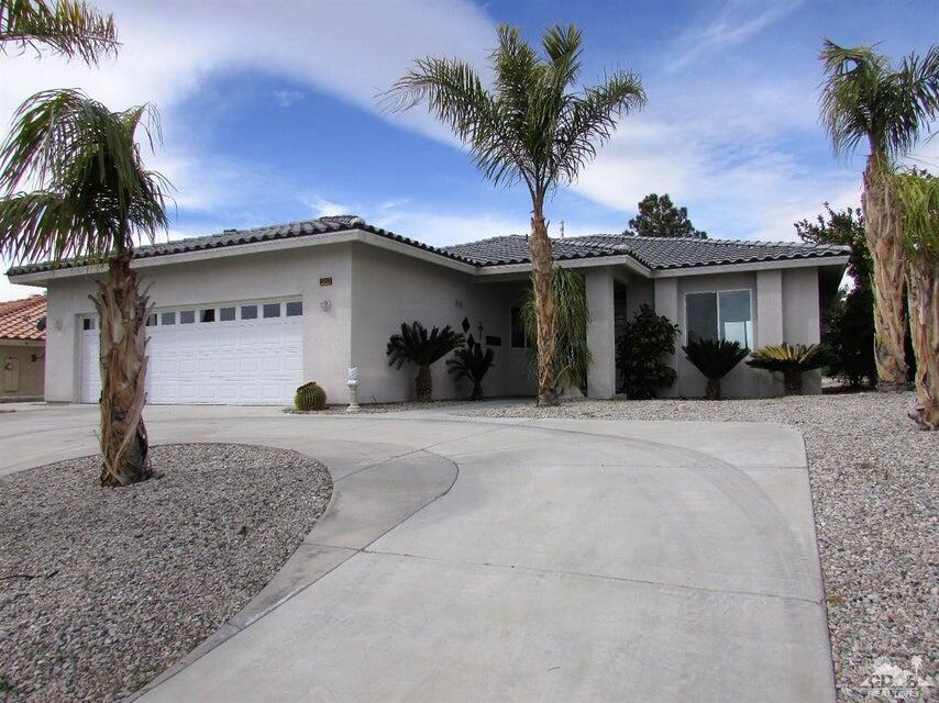 front view of a house with a yard and palm trees