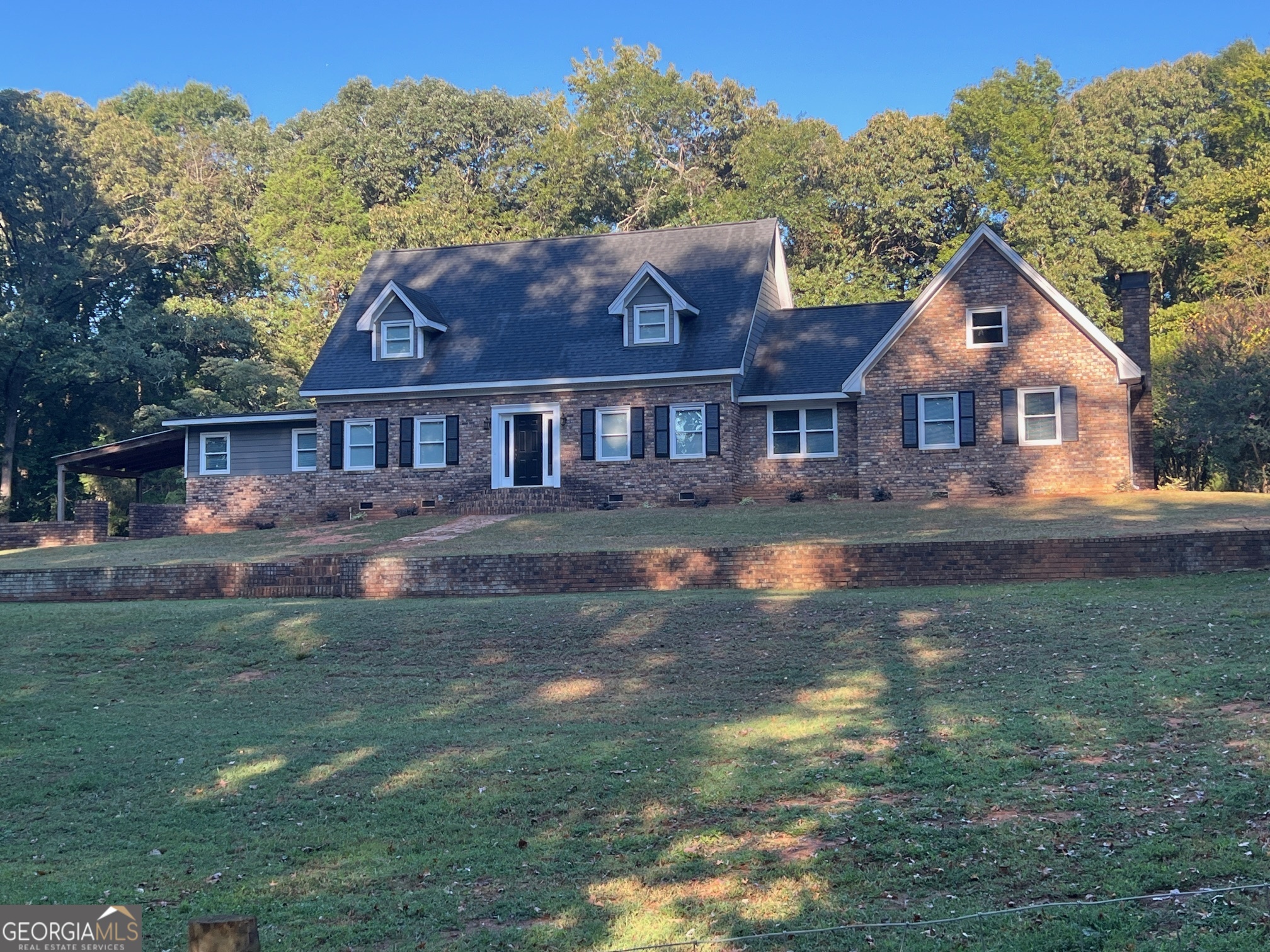 a front view of a house with a yard and mountain view in back