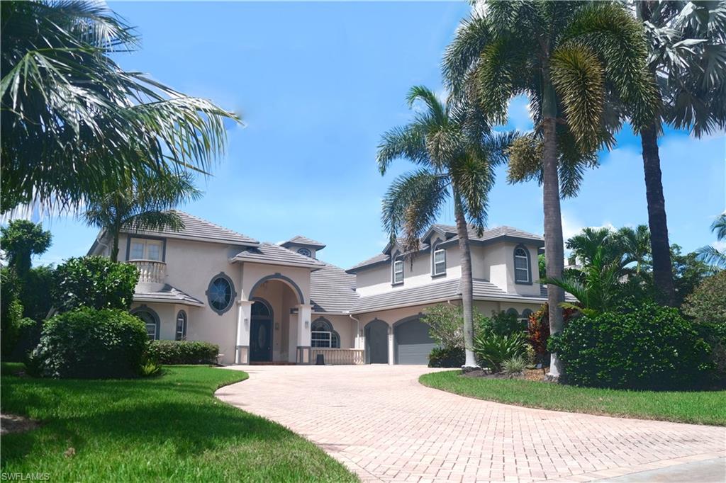 a view of a white house with a big yard plants and palm trees