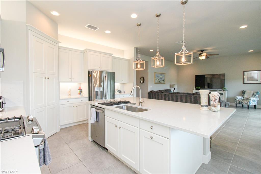 Kitchen with a kitchen island with sink, sink, ceiling fan, white cabinetry, and stainless steel appliances