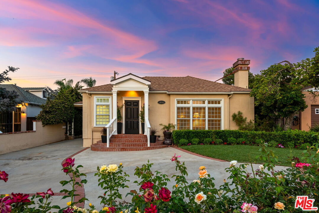 a front view of a house with a yard and potted plants