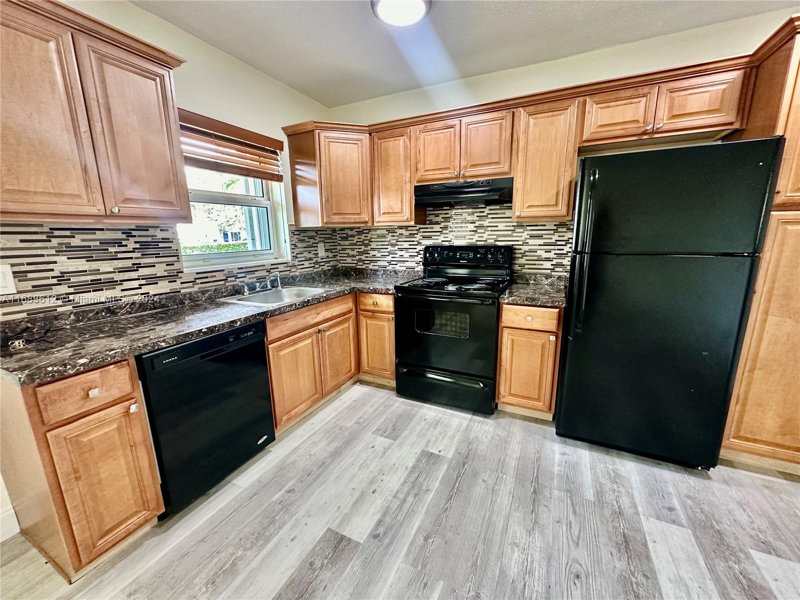 a kitchen with stainless steel appliances granite countertop a stove a refrigerator a sink and dishwasher with wooden floor