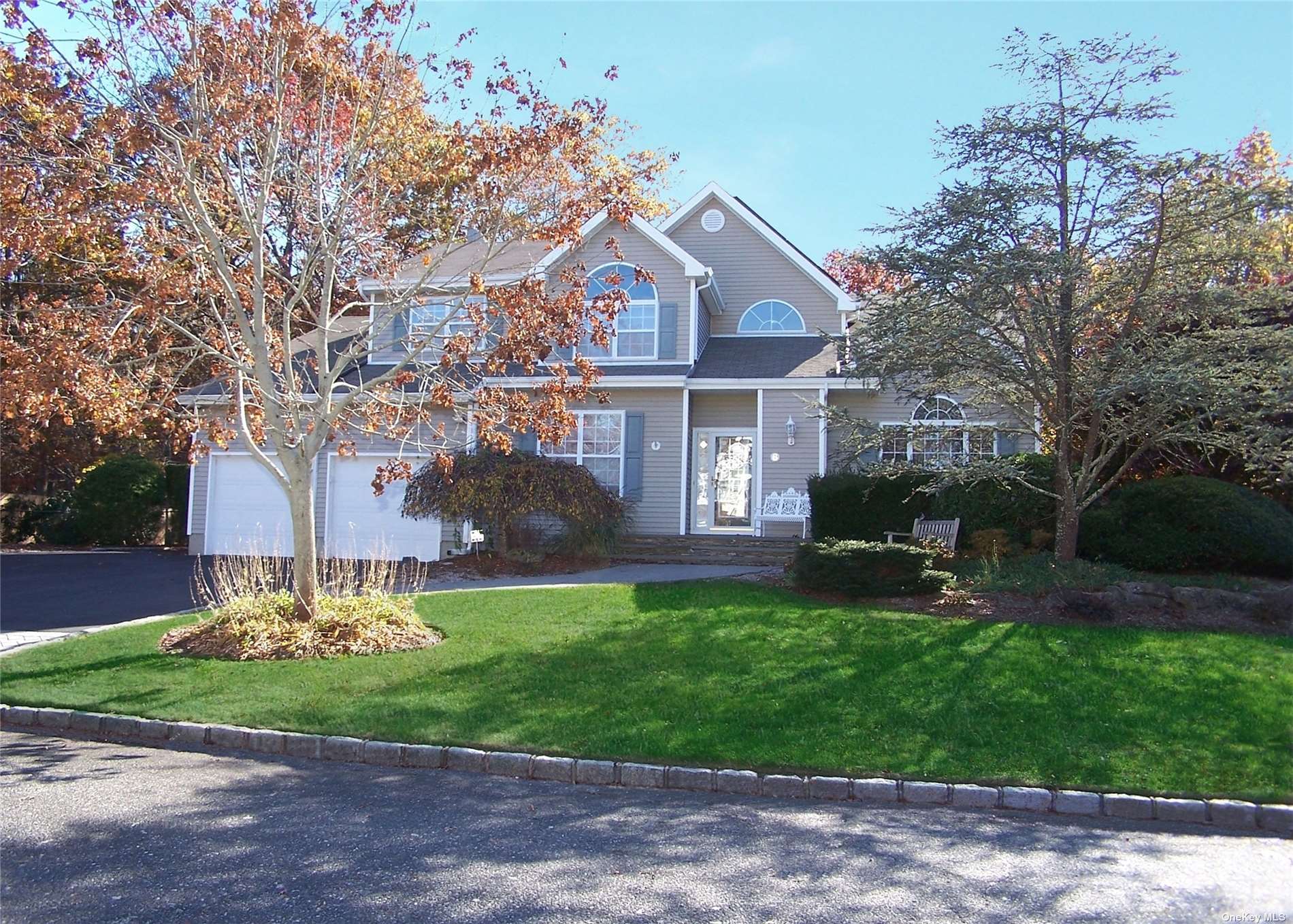 a front view of a house with a garden and trees