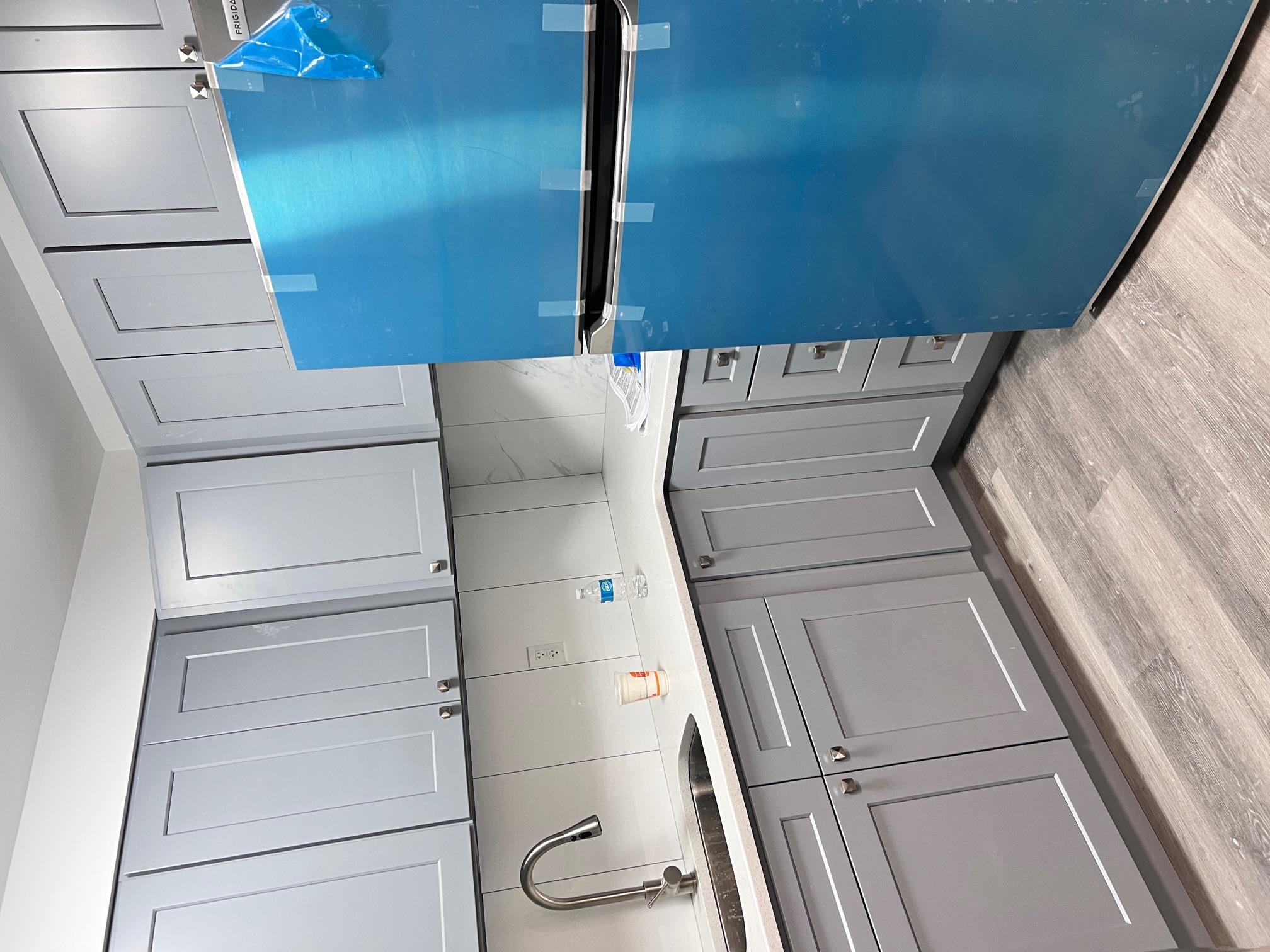 Kitchen with light wood-type flooring, refrigerator, gray cabinetry, and sink