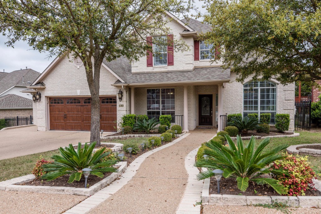 a view of a house with a small yard plants and large tree