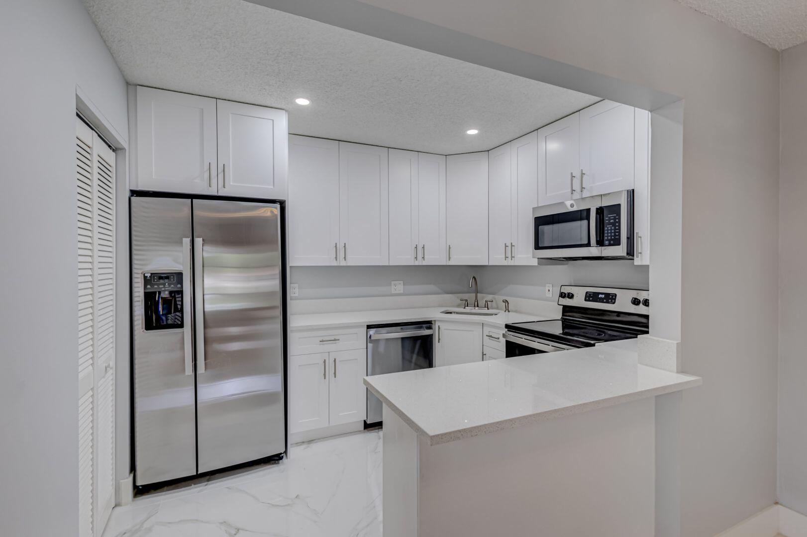 a kitchen with a refrigerator a microwave a sink and cabinets