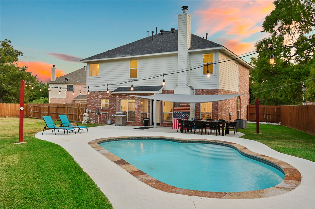 Pool at dusk featuring a yard, a patio, and a gril