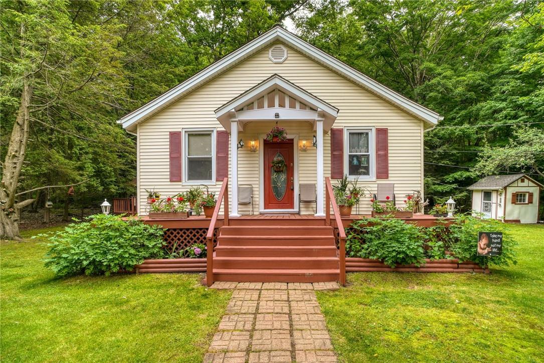 Bungalow-style house featuring a deck, a front lawn, and a shed