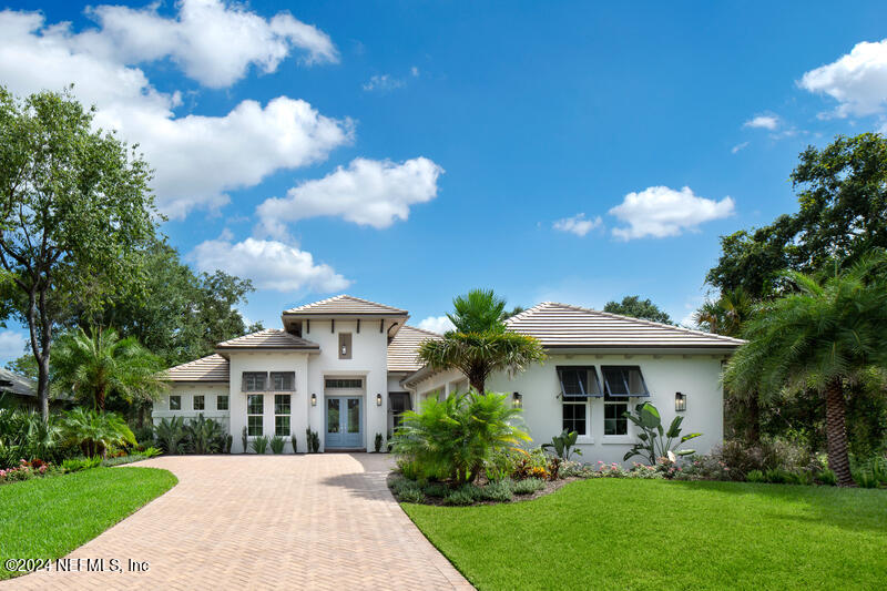 a front view of a house with garden and trees