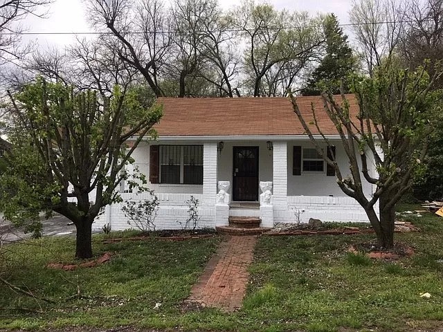 a front view of the house with yard and tree