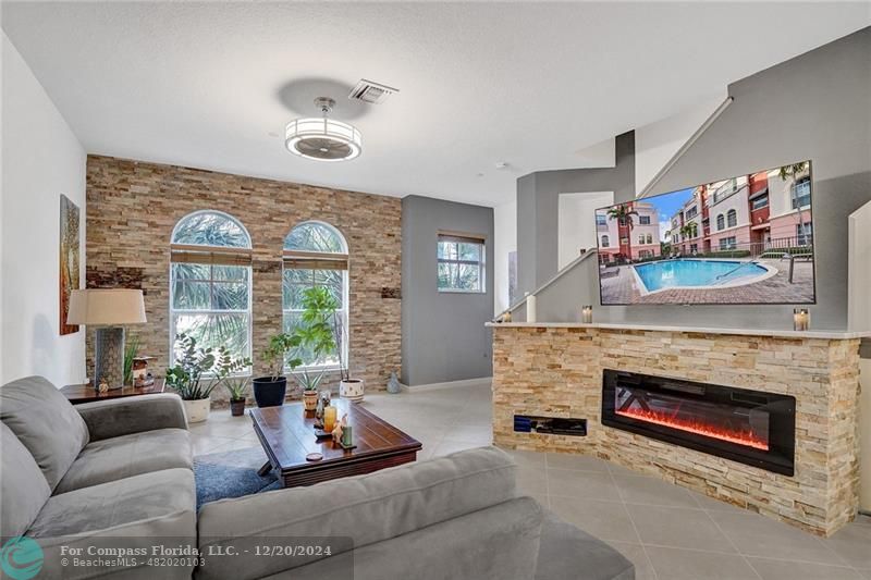 a living room with furniture a fireplace and a large window