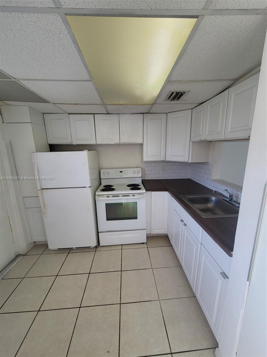 a kitchen with granite countertop a stove a sink and a refrigerator