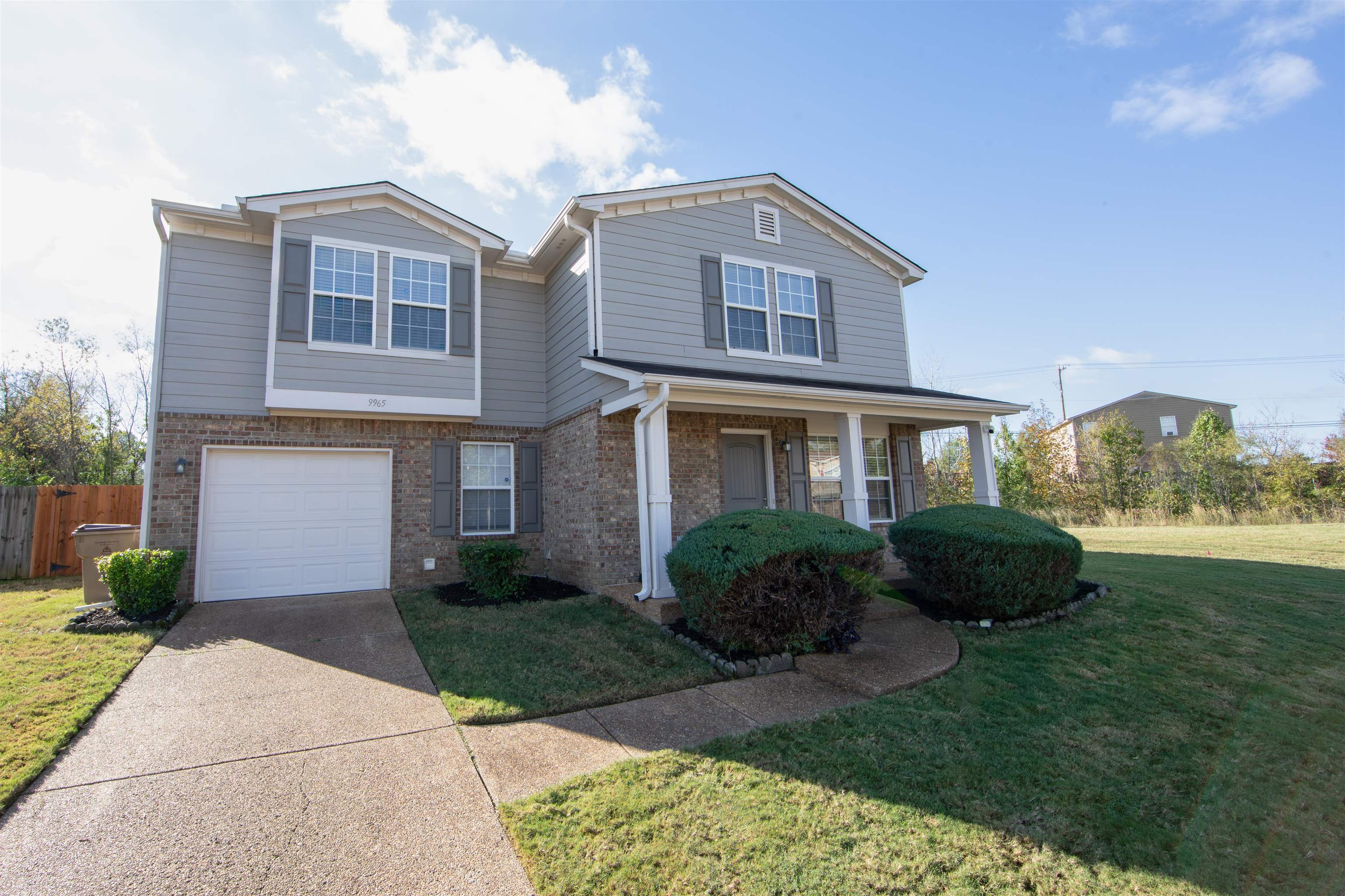 View of property with a front lawn, a porch, and a garage