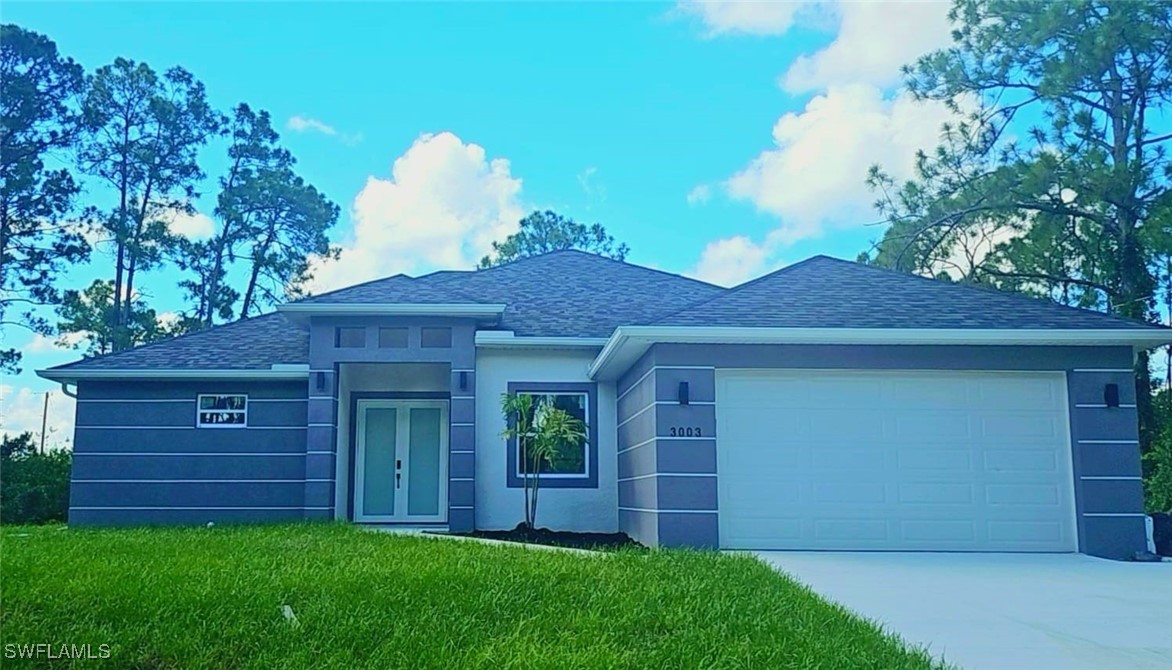 a view of a house with a small yard and a large tree