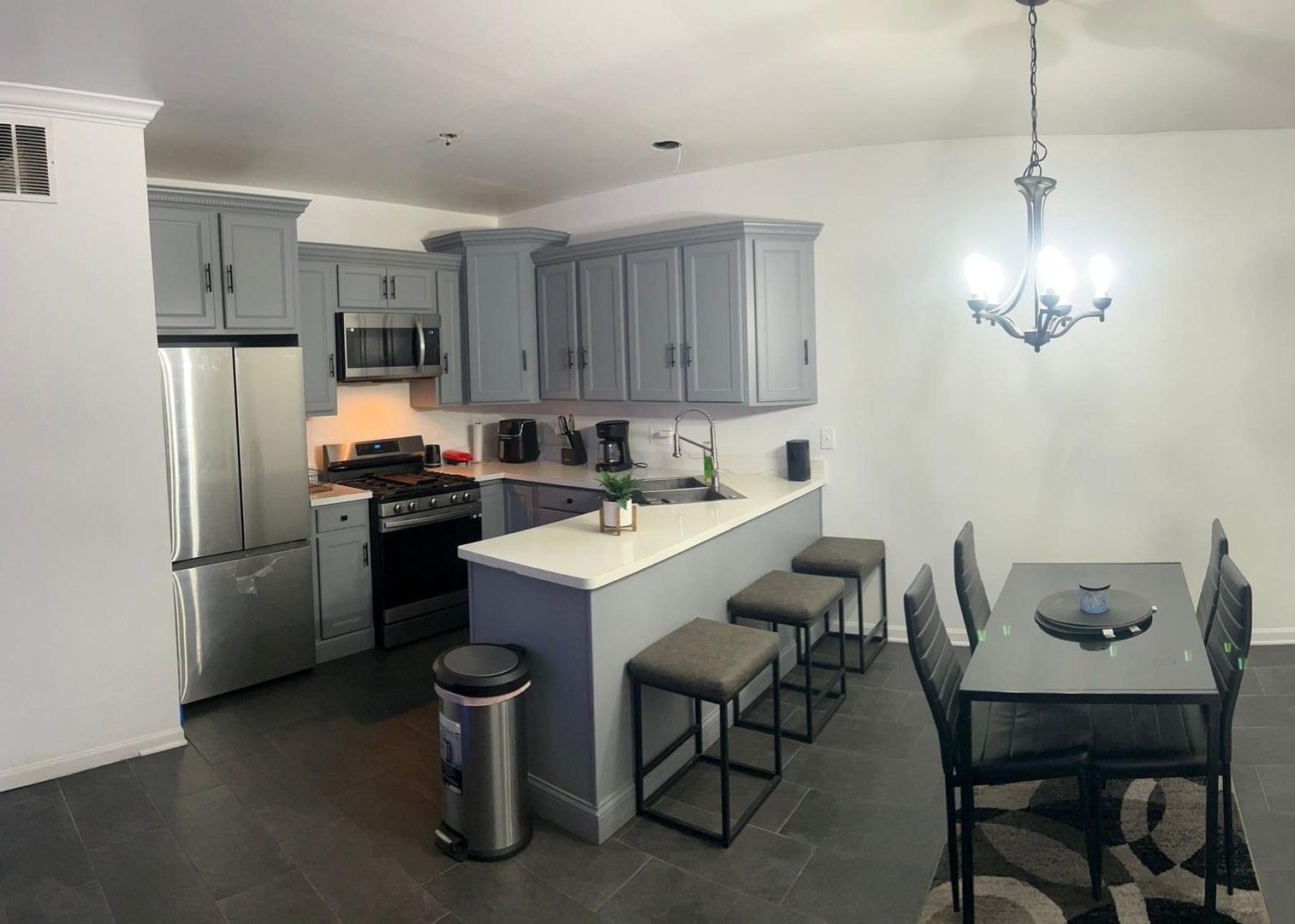 a kitchen with stainless steel appliances kitchen island a table chairs and a refrigerator