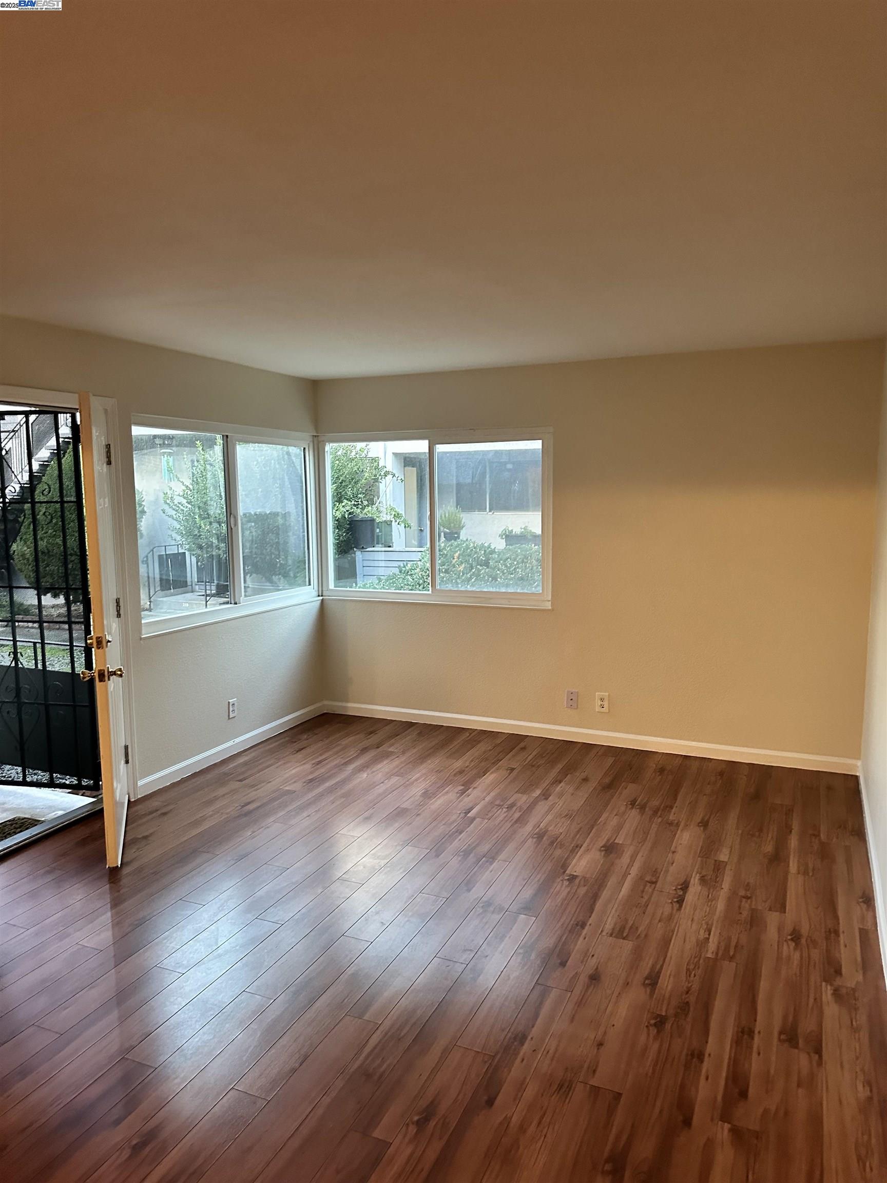 an empty room with wooden floor and windows