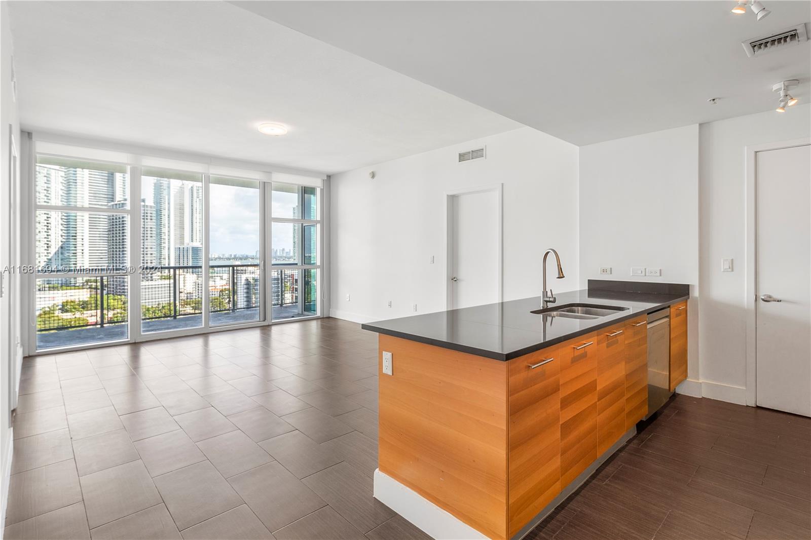 a kitchen with stainless steel appliances granite countertop a sink and a view of living room