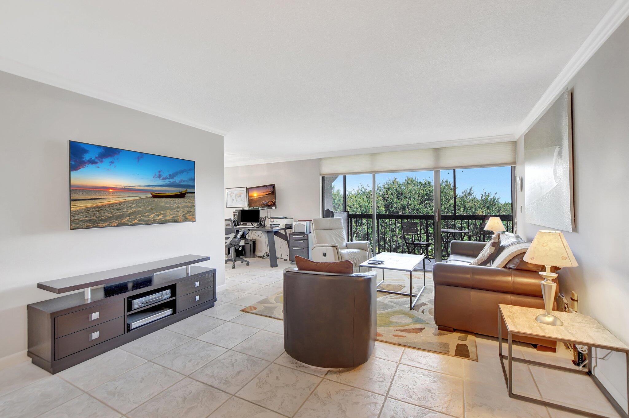 a living room with furniture a flat screen tv and a floor to ceiling window