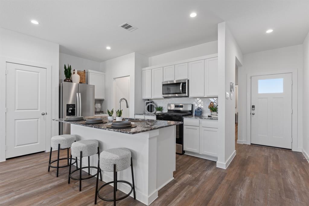 a kitchen with white cabinets and stainless steel appliances