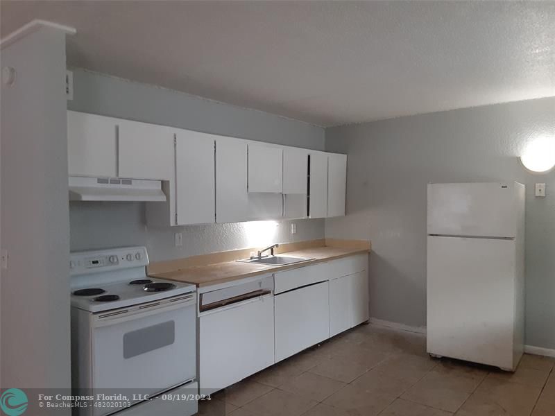 a kitchen with granite countertop white cabinets and white appliances