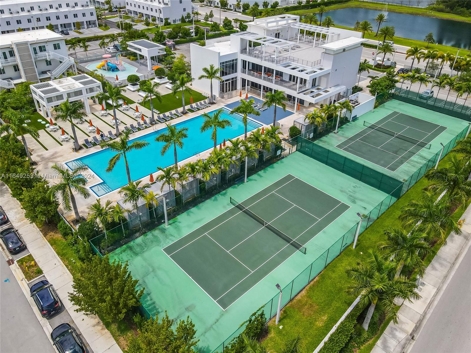 an aerial view of a tennis ground and a cars park side of the road