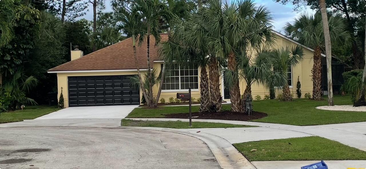 front view of house with a yard and palm trees