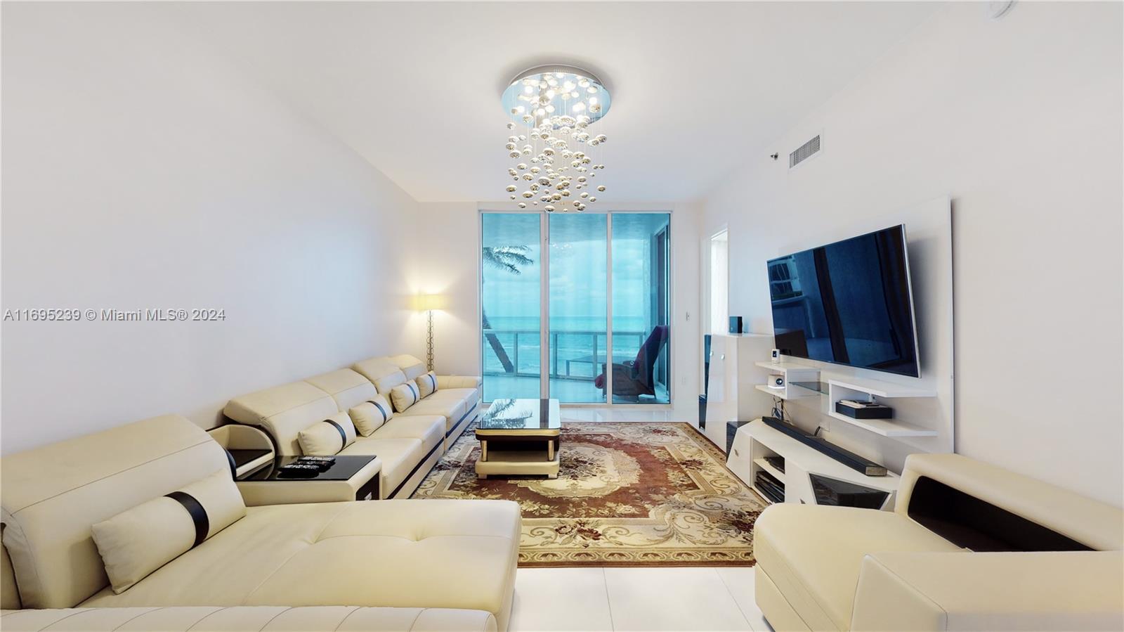 a living room with furniture a chandelier and a flat screen tv