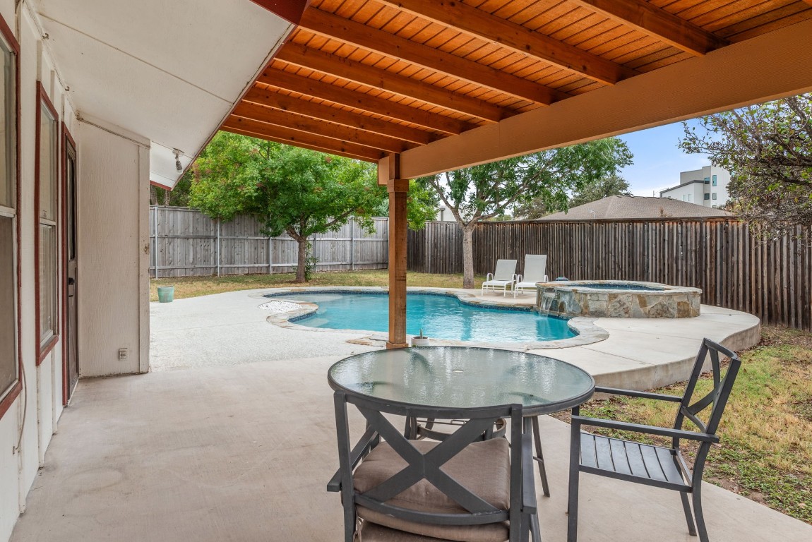 a view of a patio with a table and chairs under an umbrella with a small yard